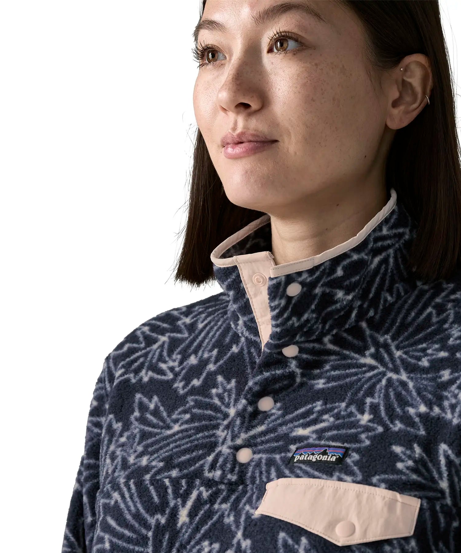 Woman wearing the Patagonia women's lightweight synchilla fleece snap-T pullover with a saxifrage pattern in a sunken blue colour. Close up of popper closure neck.