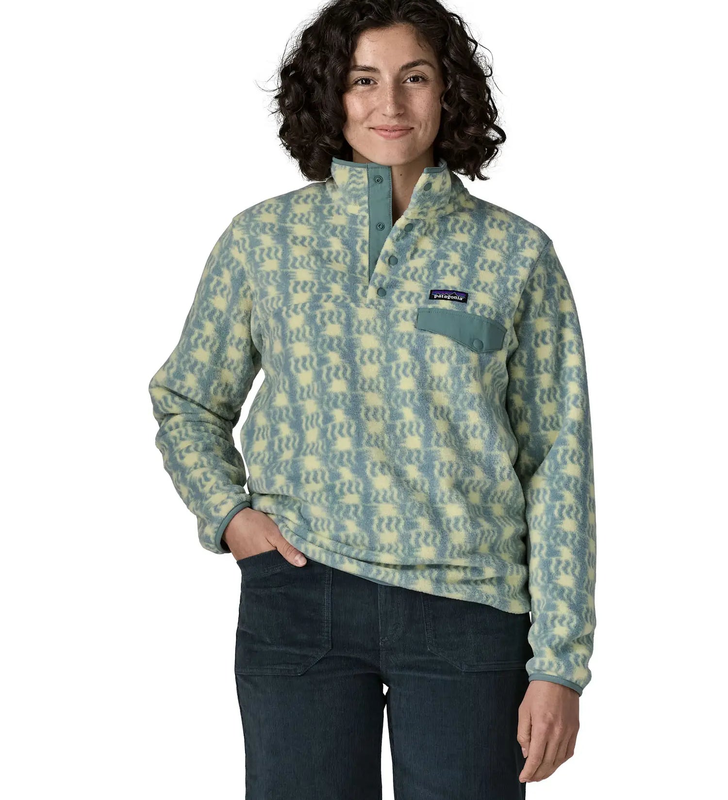 Woman wearing the Patagonia women's lightweight synchilla fleece snap-T pullover in a sun Quilt pattern in blue sage with the poppered neck closure open.