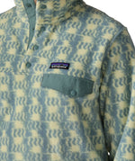 Woman wearing the Patagonia women's lightweight synchilla fleece snap-T pullover in a sun Quilt pattern in blue sage, close up of sage green chest pocket flap.