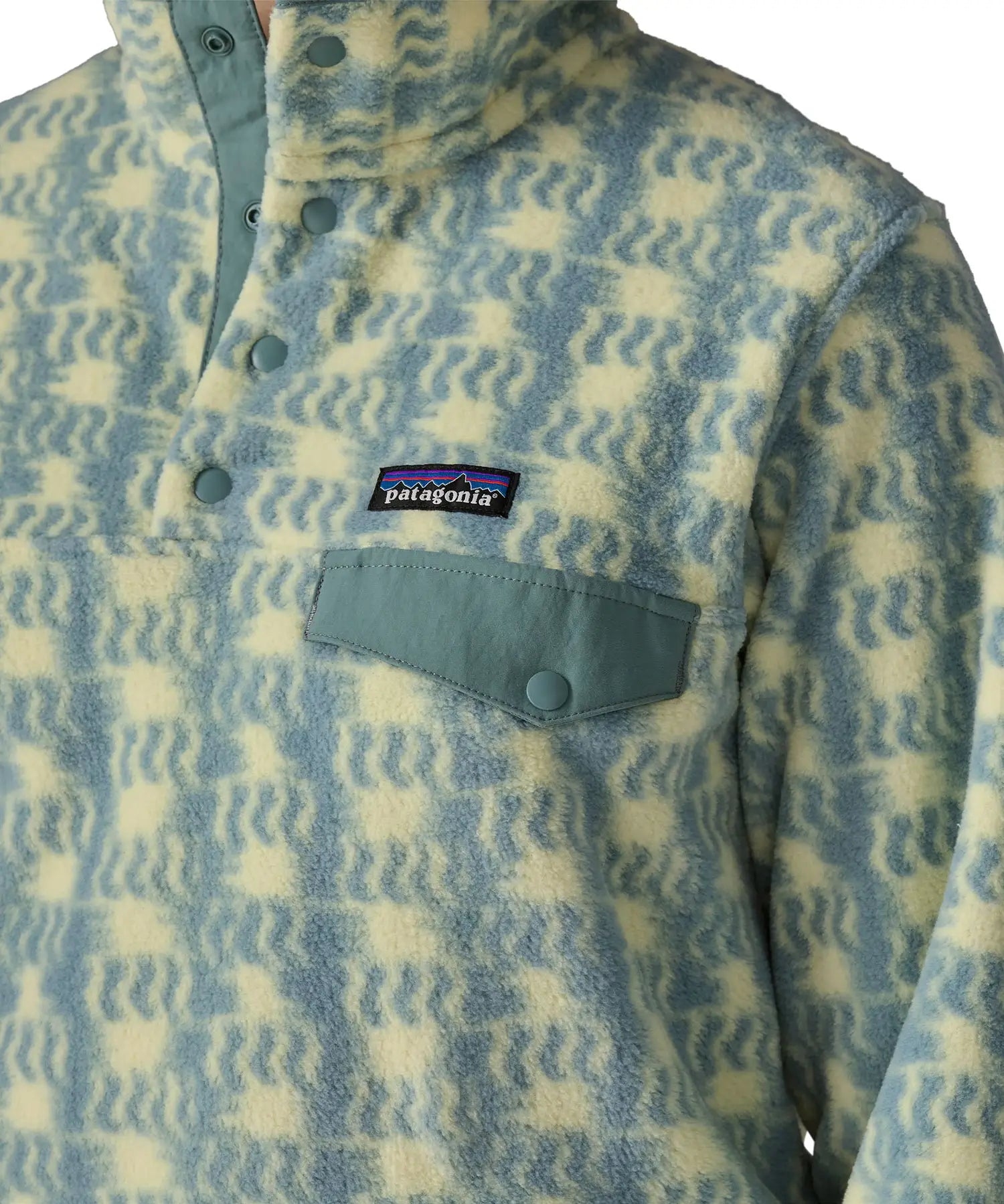 Woman wearing the Patagonia women's lightweight synchilla fleece snap-T pullover in a sun Quilt pattern in blue sage, close up of sage green chest pocket flap.
