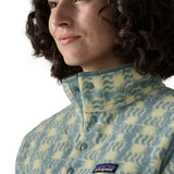 Woman wearing the Patagonia women's lightweight synchilla fleece snap-T pullover in a sun Quilt pattern in blue sage. Close up of popper neck closure.