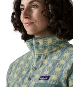 Woman wearing the Patagonia women's lightweight synchilla fleece snap-T pullover in a sun Quilt pattern in blue sage. Close up of popper neck closure.