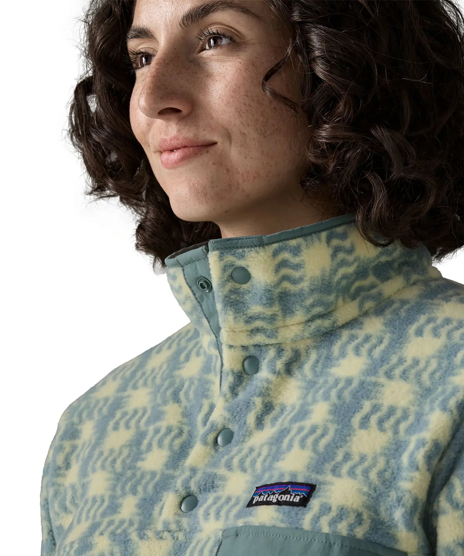 Woman wearing the Patagonia women's lightweight synchilla fleece snap-T pullover in a sun Quilt pattern in blue sage. Close up of popper neck closure.