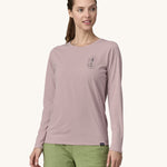A woman wearing a Patagonia Women's Long-Sleeved Capilene Cool Shirt with a  Clean Climb Bloom graphic on the left chest in an Echo Purple colour.