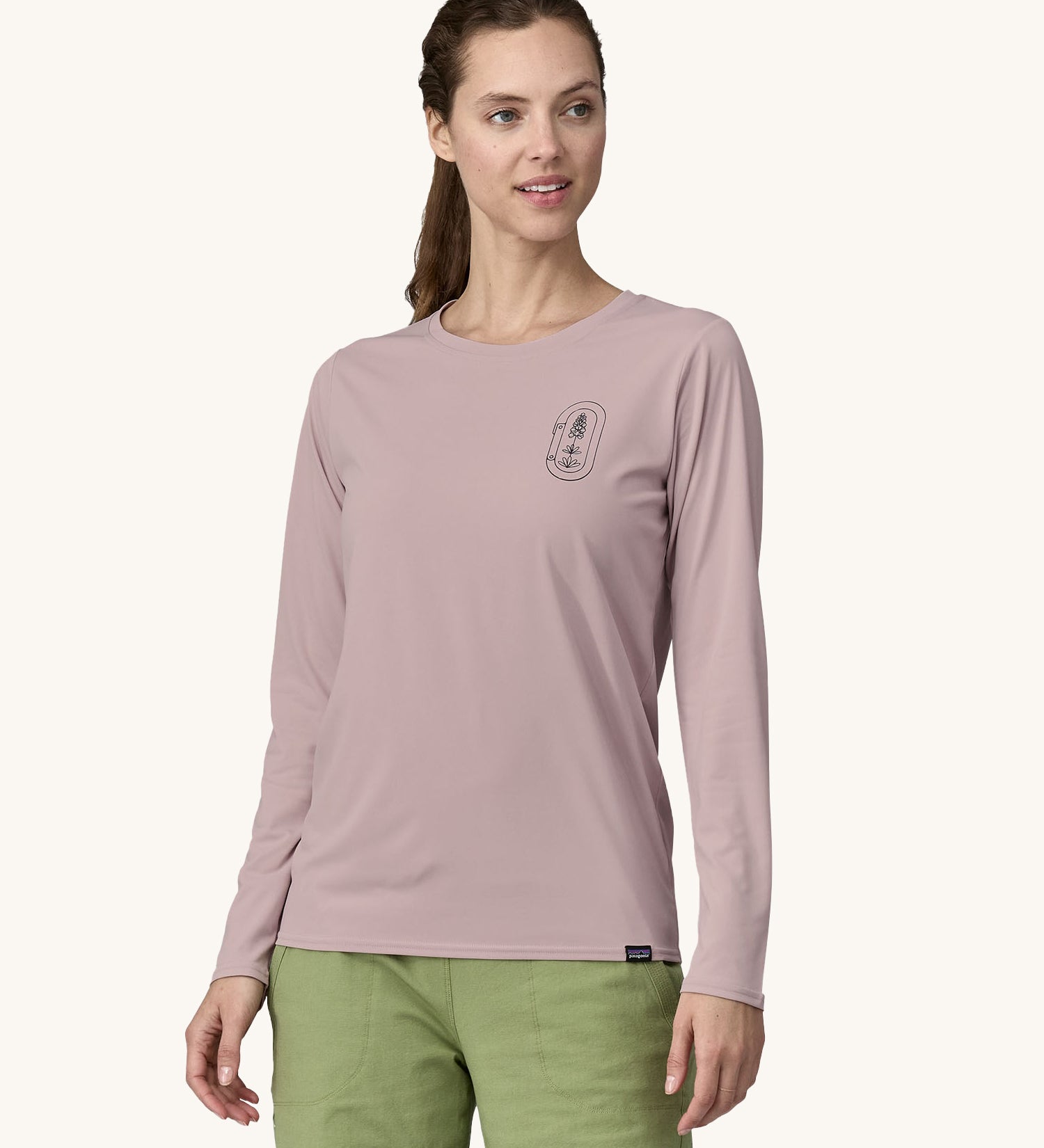 A woman wearing a Patagonia Women's Long-Sleeved Capilene Cool Shirt with a  Clean Climb Bloom graphic on the left chest in an Echo Purple colour.