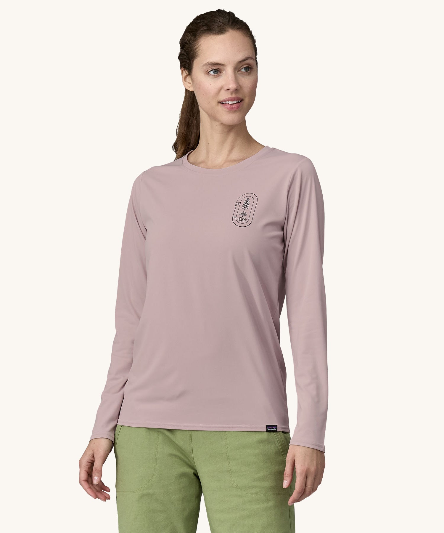 A woman wearing a Patagonia Women's Long-Sleeved Capilene Cool Shirt with a  Clean Climb Bloom graphic on the left chest in an Echo Purple colour.