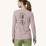 A woman wearing the back of the Patagonia Women's Long-Sleeved Capilene Cool Shirt with a  Clean Climb Bloom graphic in an Echo Purple colour showing the back of the top.