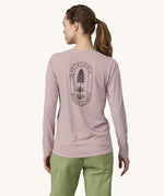 A woman wearing the back of the Patagonia Women's Long-Sleeved Capilene Cool Shirt with a  Clean Climb Bloom graphic in an Echo Purple colour showing the back of the top.