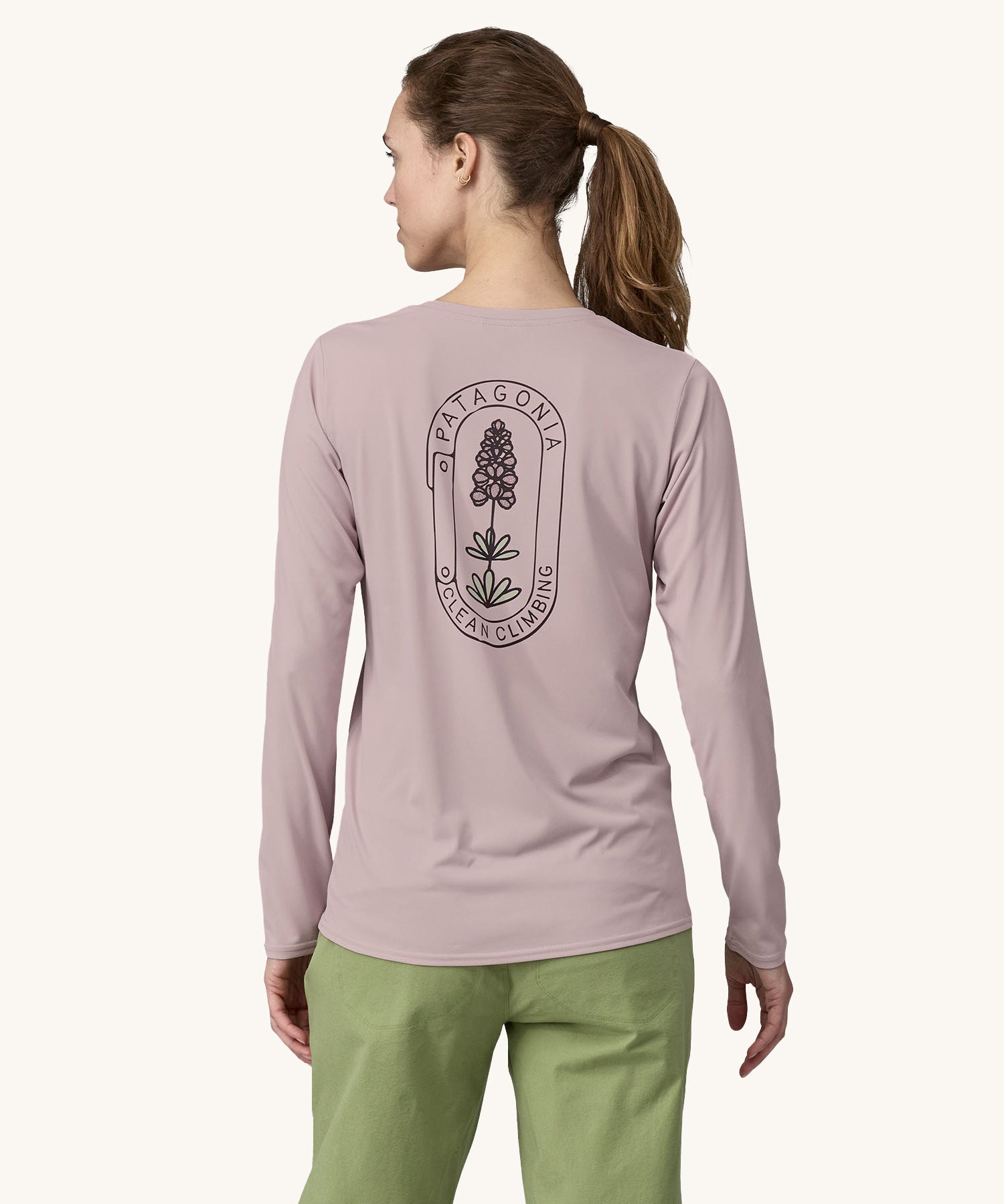 A woman wearing the back of the Patagonia Women's Long-Sleeved Capilene Cool Shirt with a  Clean Climb Bloom graphic in an Echo Purple colour showing the back of the top.