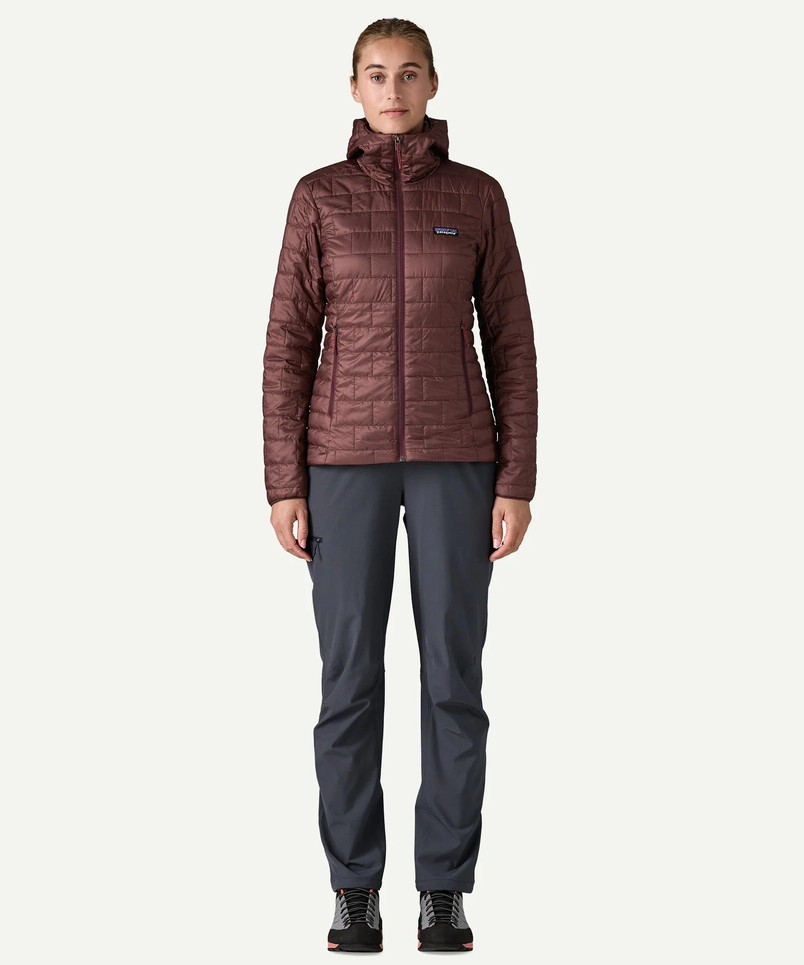 Woman wearing the Patagonia Women’s Nano Puff Hoody in Dark Ruby, lightweight insulated recycled polyester jacket for hiking and outdoor wear.