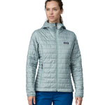 A woman wearing a Patagonia Women's Nano Puff Hoody in Thermal Blue showing the front of the jacket. The front is fully zipped up. 