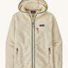 Patagonia Retro Pile Hoody. A women's fleece style jacket in a light cream colour with green trim. Features a full length zip, 2 side pockets, a chest pocket and a logo patch stitched on the left chest.