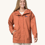 A woman wearing the Patagonia Women's Outdoor Everyday Rain Jacket in a Sienna Clay colour.