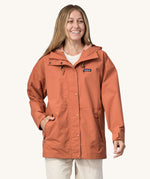 A woman wearing the Patagonia Women's Outdoor Everyday Rain Jacket in a Sienna Clay colour.