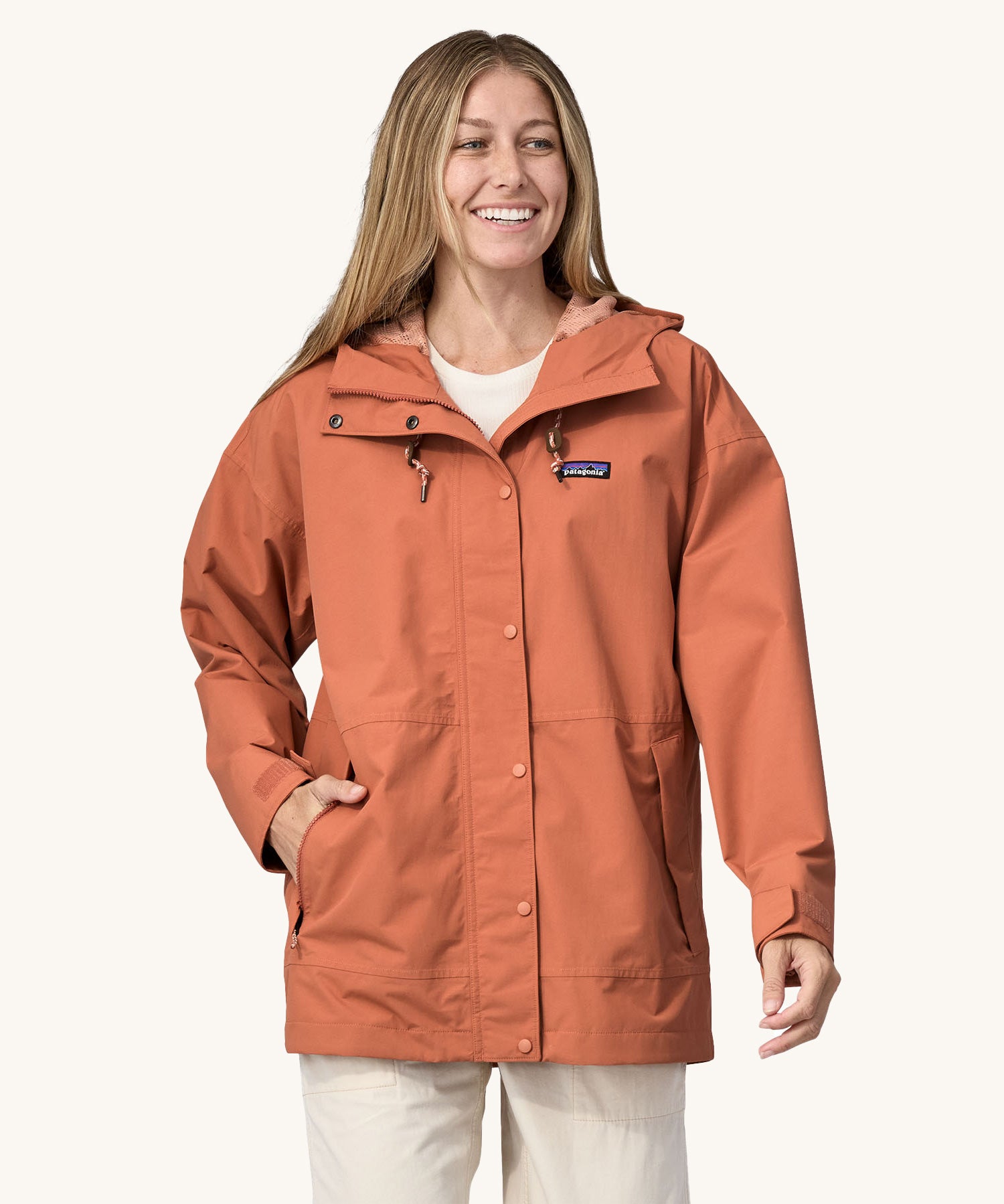 A woman wearing the Patagonia Women's Outdoor Everyday Rain Jacket in a Sienna Clay colour.