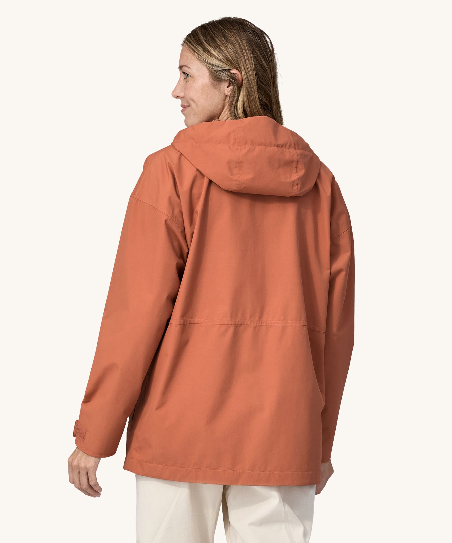 A woman wearing the Patagonia Women's Outdoor Everyday Rain Jacket in a Sienna Clay colour.