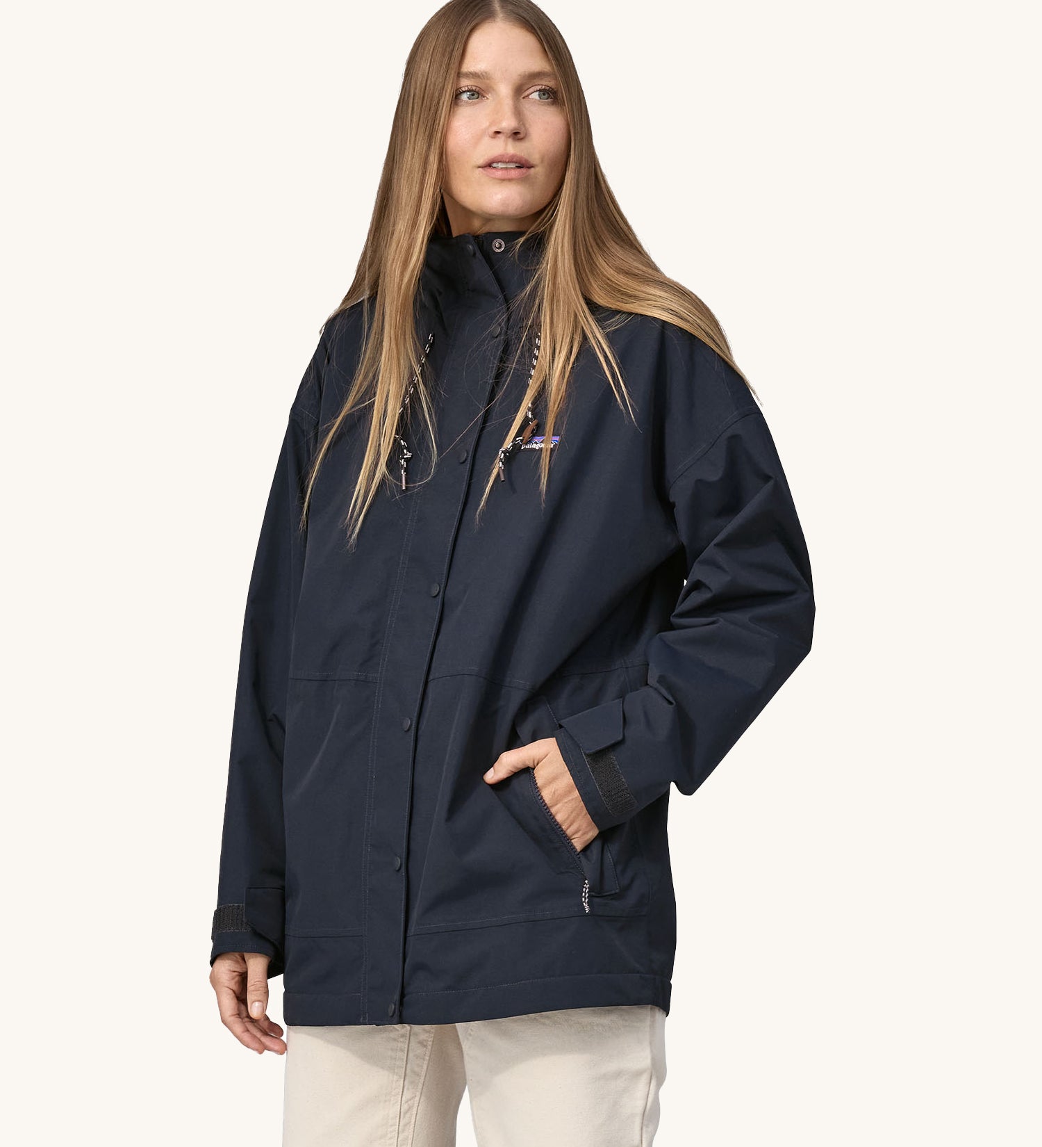 A woman wearing a Patagonia Women's Outdoor Everyday Rain Jacket in a Pitch Blue colour. The zip of the coat is fully closed.