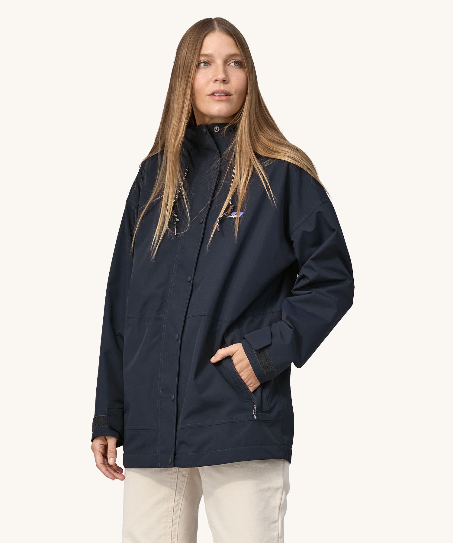 A woman wearing a Patagonia Women's Outdoor Everyday Rain Jacket in a Pitch Blue colour. The zip of the coat is fully closed.
