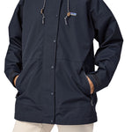 A close up of a woman wearing a Patagonia Women's Outdoor Everyday Rain Jacket in a Pitch Blue colour. The zip of the coat is fully closed.
