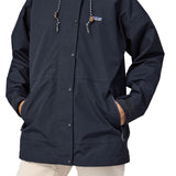 A close up of a woman wearing a Patagonia Women's Outdoor Everyday Rain Jacket in a Pitch Blue colour. The zip of the coat is fully closed.