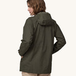 A woman wearing a Patagonia Women's Outdoor Everyday Rain Jacket in a Pine Needle Green colour. The woman is facing away from the camera showing the back of the jacket. 