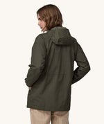 A woman wearing a Patagonia Women's Outdoor Everyday Rain Jacket in a Pine Needle Green colour. The woman is facing away from the camera showing the back of the jacket. 