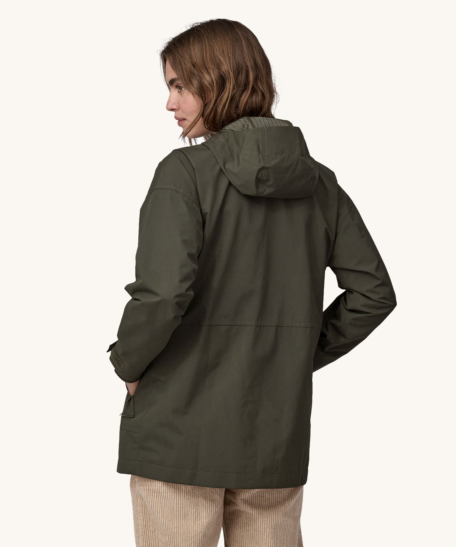 A woman wearing a Patagonia Women's Outdoor Everyday Rain Jacket in a Pine Needle Green colour. The woman is facing away from the camera showing the back of the jacket. 