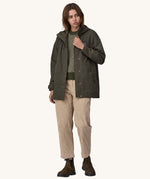 A woman wearing a Patagonia Women's Outdoor Everyday Rain Jacket in a Pine Needle Green colour. The zip of the coat is fully open.