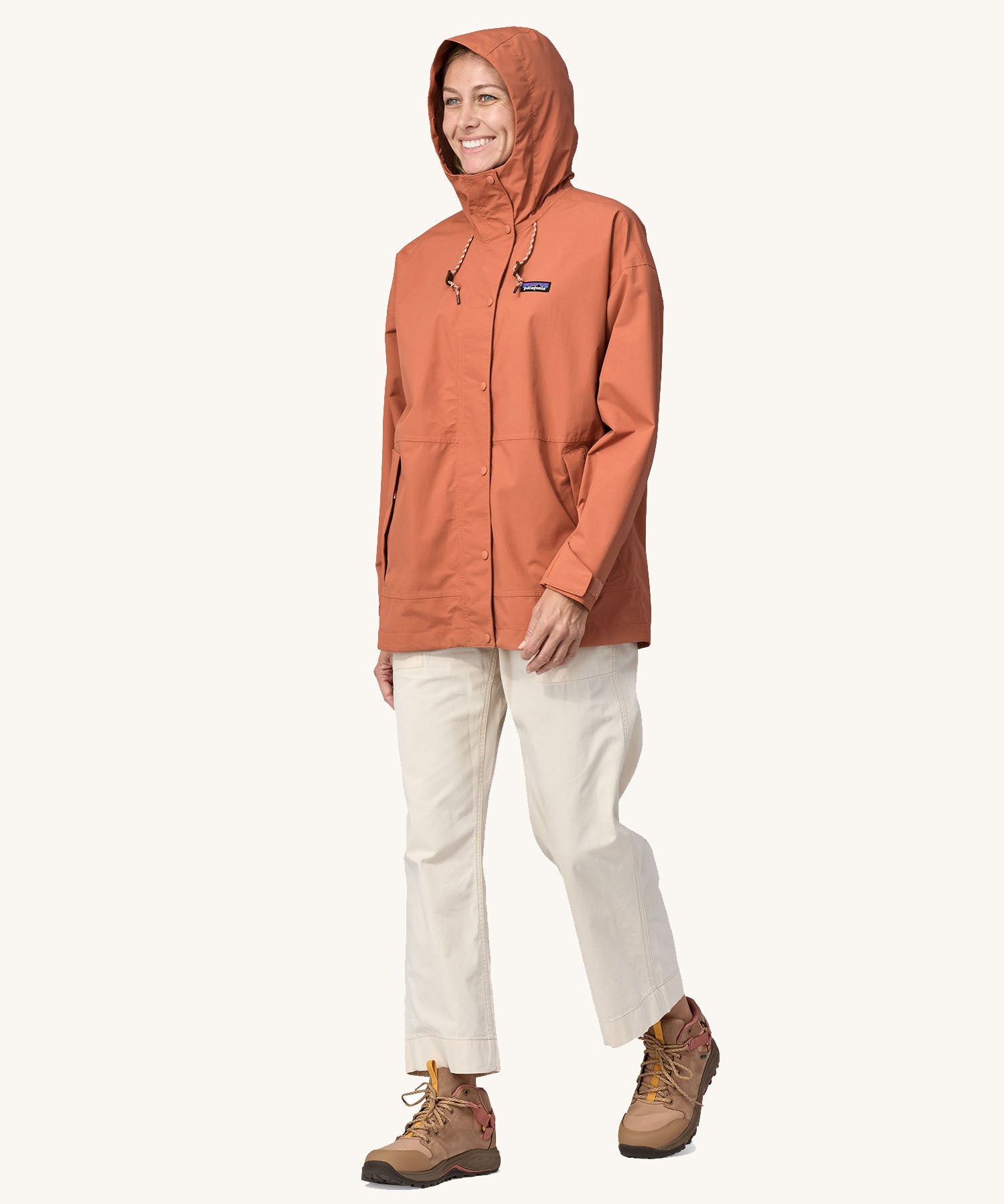 A woman wearing the Patagonia Women's Outdoor Everyday Rain Jacket in a Sienna Clay colour.