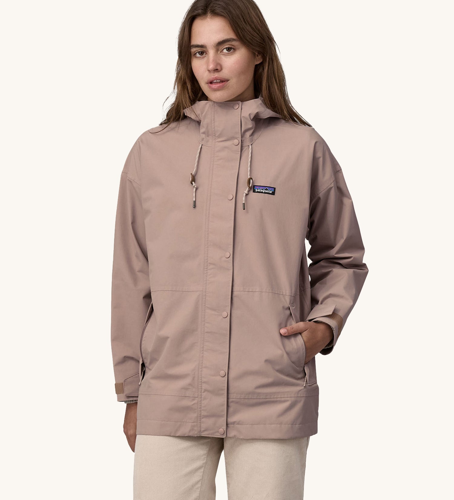 A woman wearing a Patagonia Women's Outdoor Everyday Rain Jacket in a Stingray Mauve colour. 