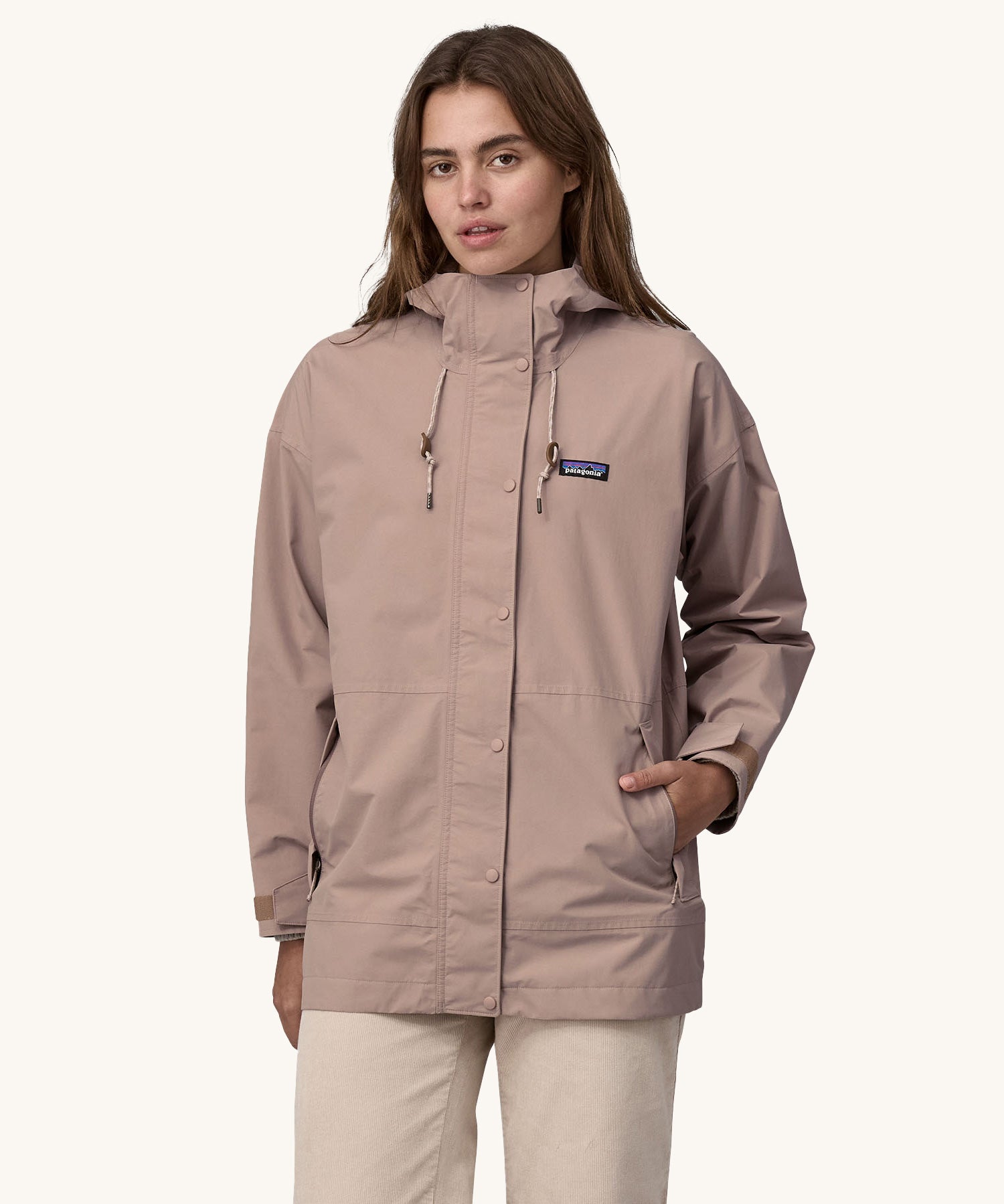 A woman wearing a Patagonia Women's Outdoor Everyday Rain Jacket in a Stingray Mauve colour. 