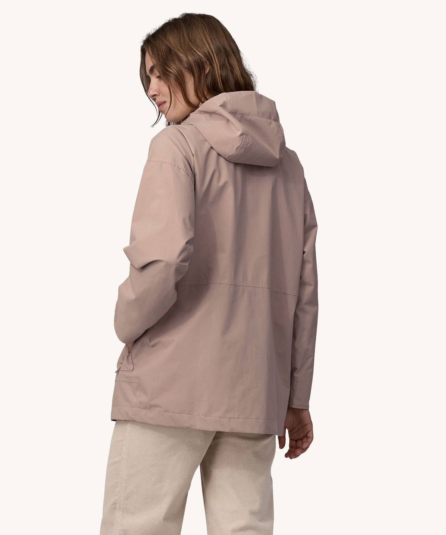 A woman wearing a Patagonia Women's Outdoor Everyday Rain Jacket in a Stingray Mauve colour. The woman is facing away from the camera showing the back of the jacket. 