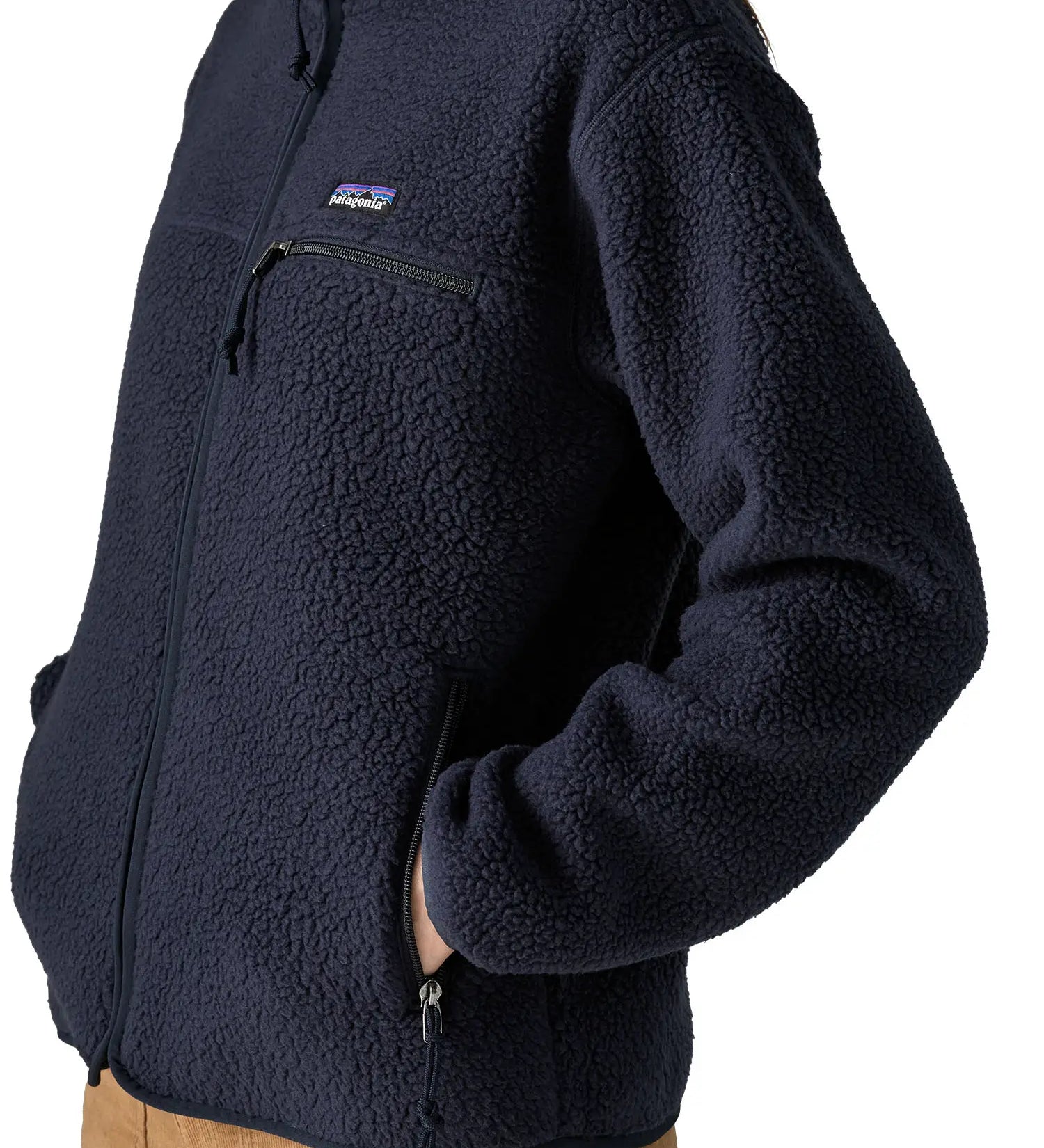 Woman wearing the Patagonia women's retro pile fleece jacket in sunken blue with zippered chest pocket with hands in the handwarmer pockets. Close up view.