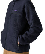 Woman wearing the Patagonia women's retro pile fleece jacket in sunken blue with zippered chest pocket with hands in the handwarmer pockets. Close up view.