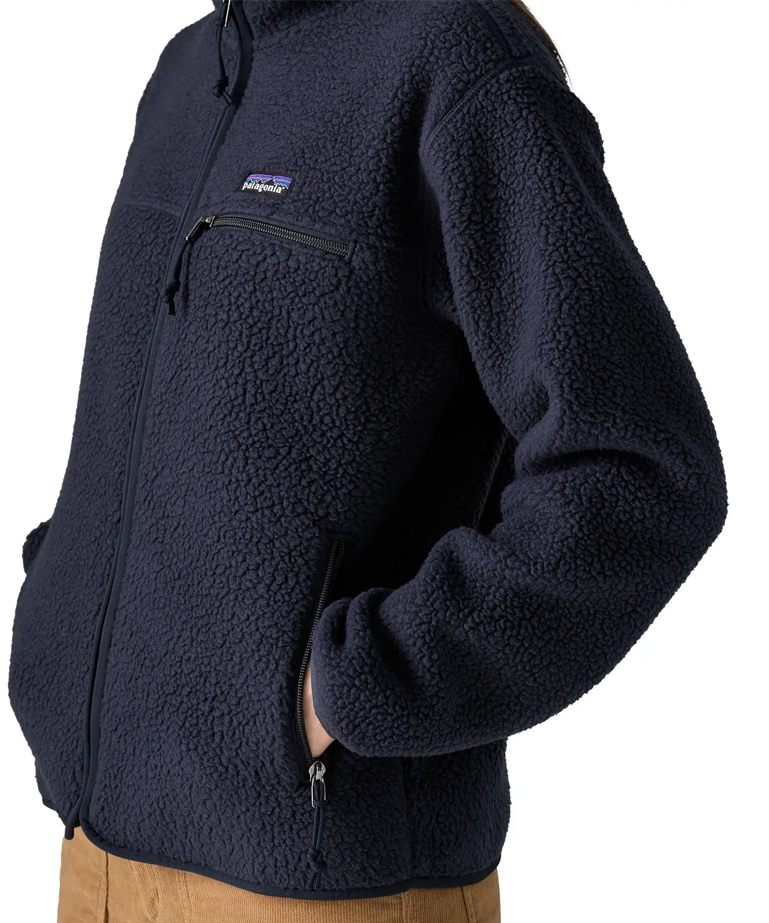 Woman wearing the Patagonia women's retro pile fleece jacket in sunken blue with zippered chest pocket with hands in the handwarmer pockets. Close up view.