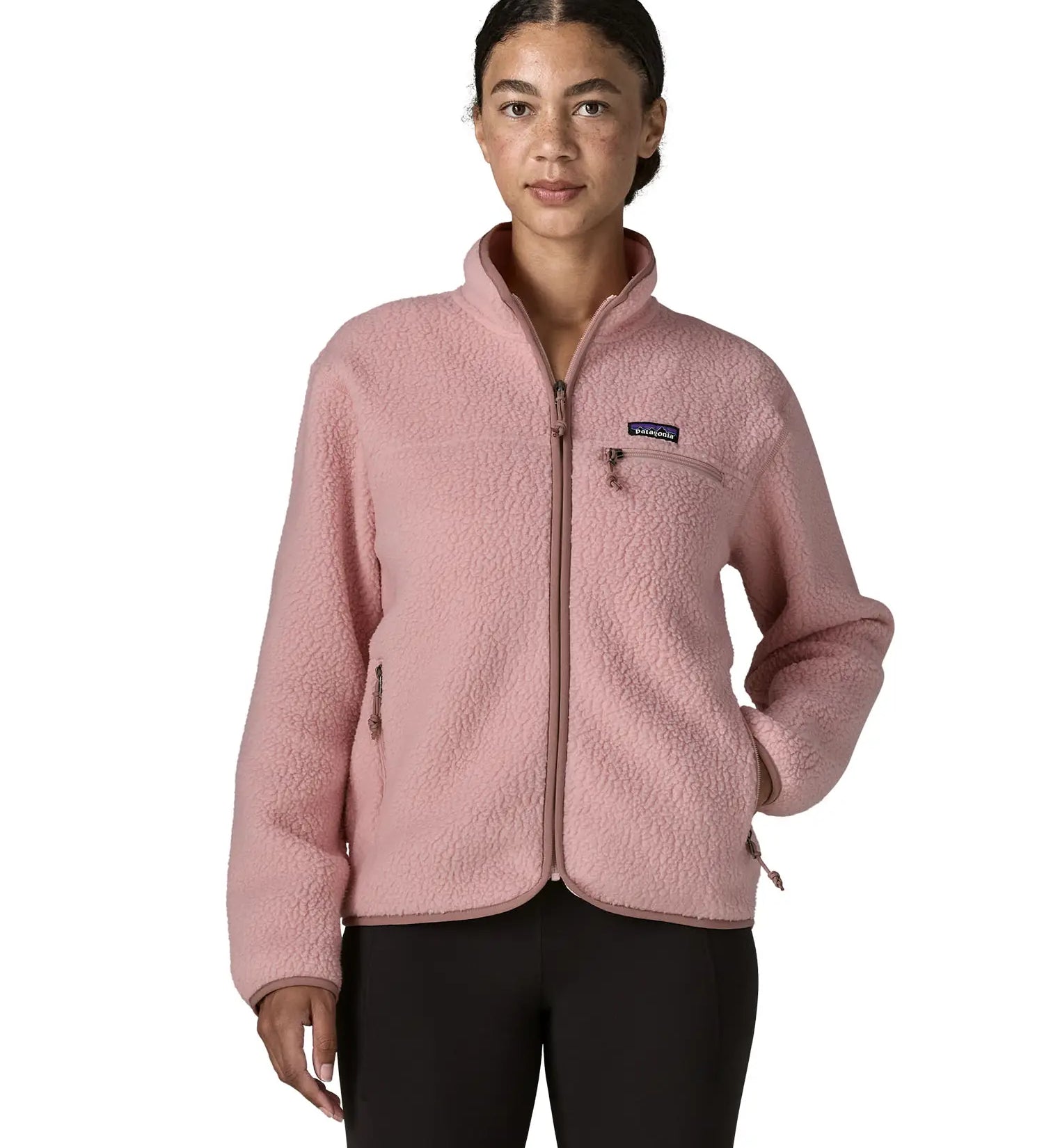 Woman wearing the Patagonia women's retro pile fleece jacket in fuzzy mauve pink. Full zip fleece jacket with zippererd chest and hand warmer pockets.