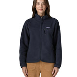 Woman wearing Patagonia women's retro pile fleece jacket in sunken blue with zippered chest pocket and handwarmer pockets.