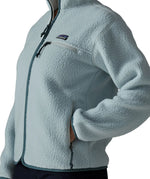 Close up of woman wearing the Patagonia women's retro pile fleece jacket in virtually blue with a hand in the hand warmer pocket.