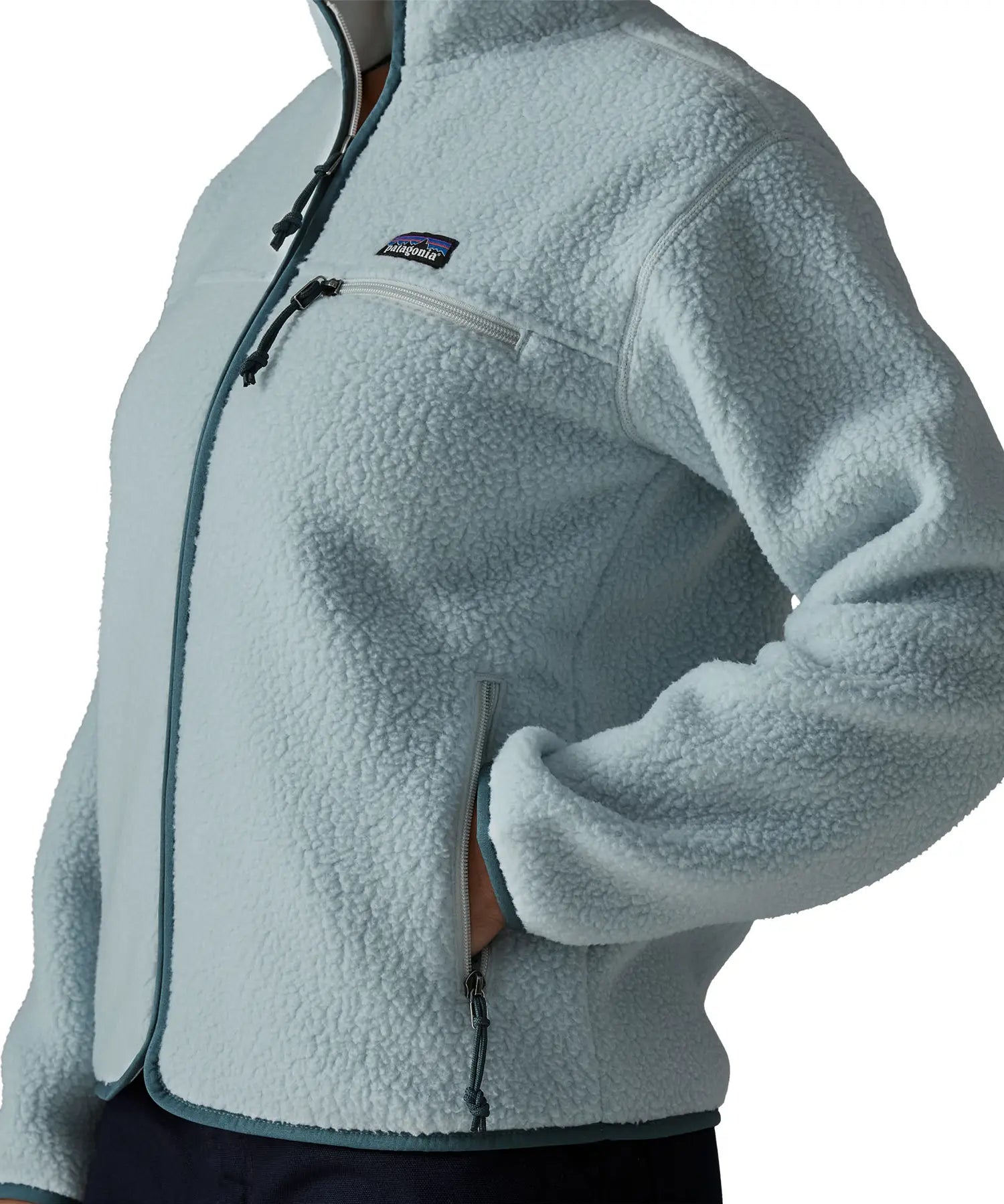 Close up of woman wearing the Patagonia women's retro pile fleece jacket in virtually blue with a hand in the hand warmer pocket.