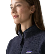 Woman wearing the Patagonia women's retro pile fleece marsupial top in dark sunken blue. Close up of half zip on front.