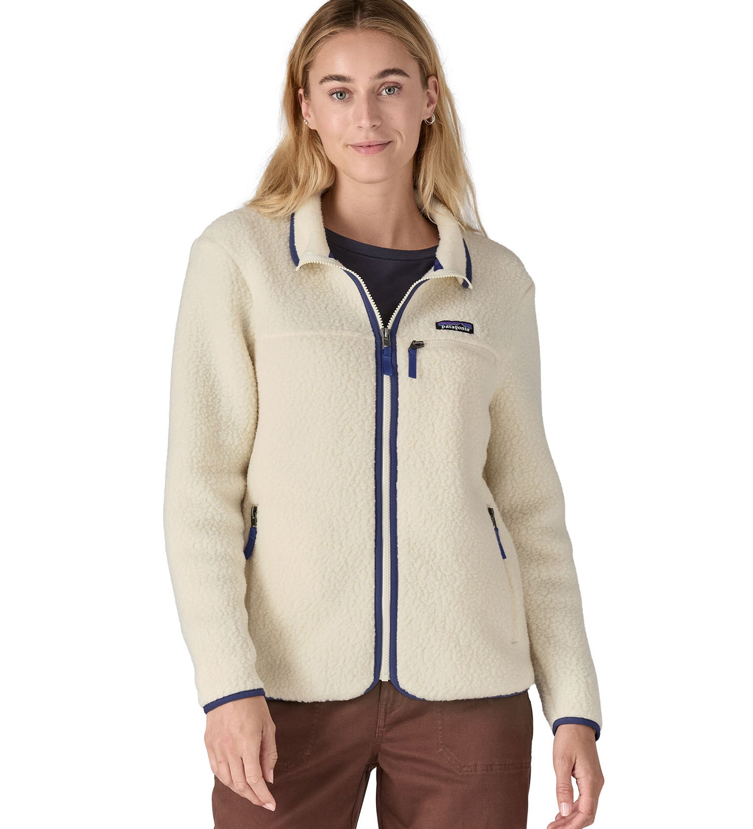 A woman wearing the Patagonia women's retro pile fleece i natural colour available at Babipur. A thick light purple fleece with a contrast blue trim. Features a full length zip, 2 side pockets and a chest pocket with the brand patch stitched above.