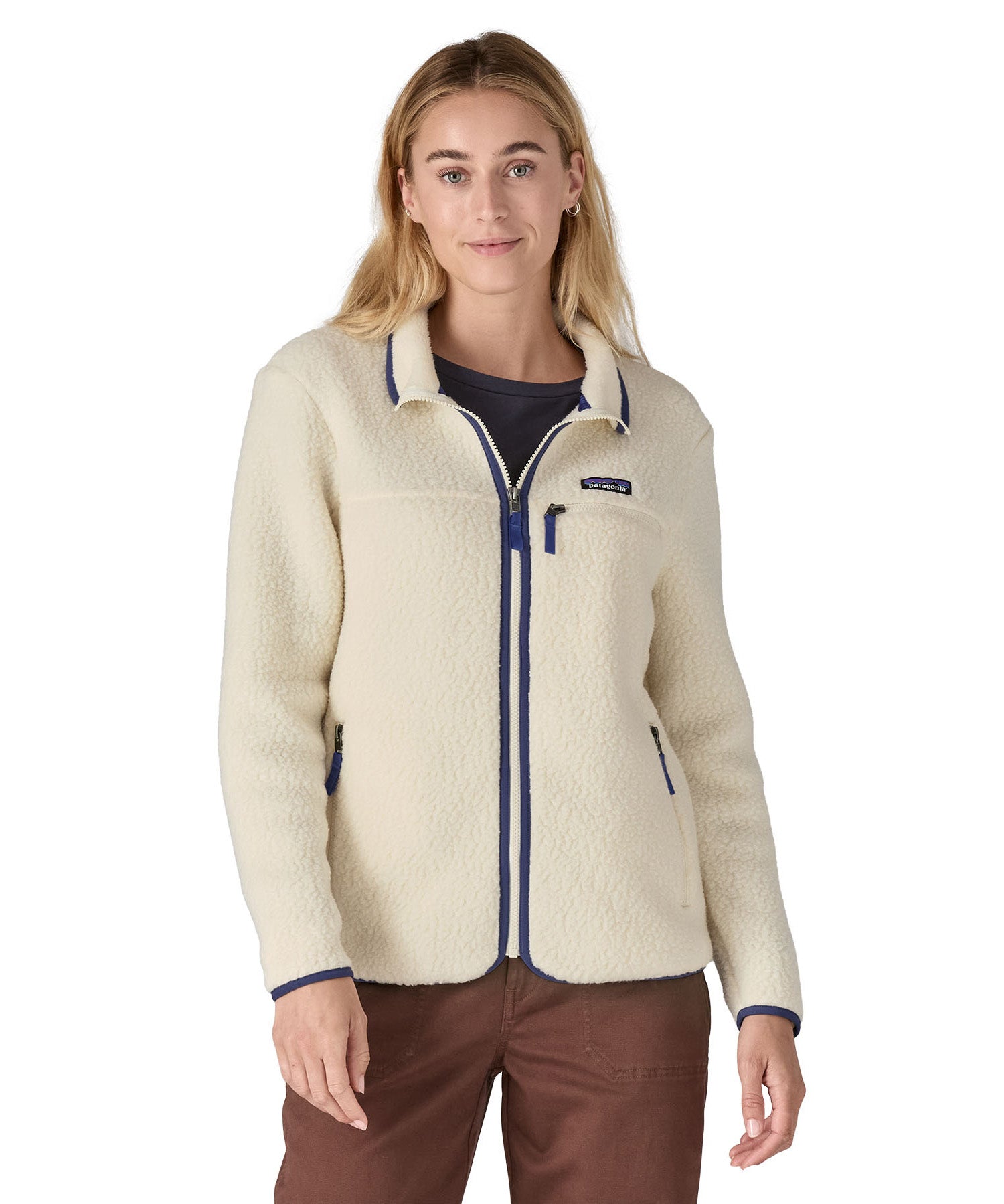 A woman wearing the Patagonia women's retro pile fleece i natural colour available at Babipur. A thick light purple fleece with a contrast blue trim. Features a full length zip, 2 side pockets and a chest pocket with the brand patch stitched above.