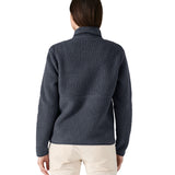 A woman with dark long hair wearing a Patagonia Women's Retro Pile Marsupial jacket in a grey colour showing the back of the jacket.