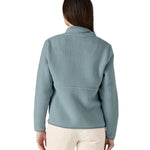 A woman with long dark hair wearing the Patagonia Women's Retro Pile Marsupial Thermal Blue  showing the back of the jacket 
