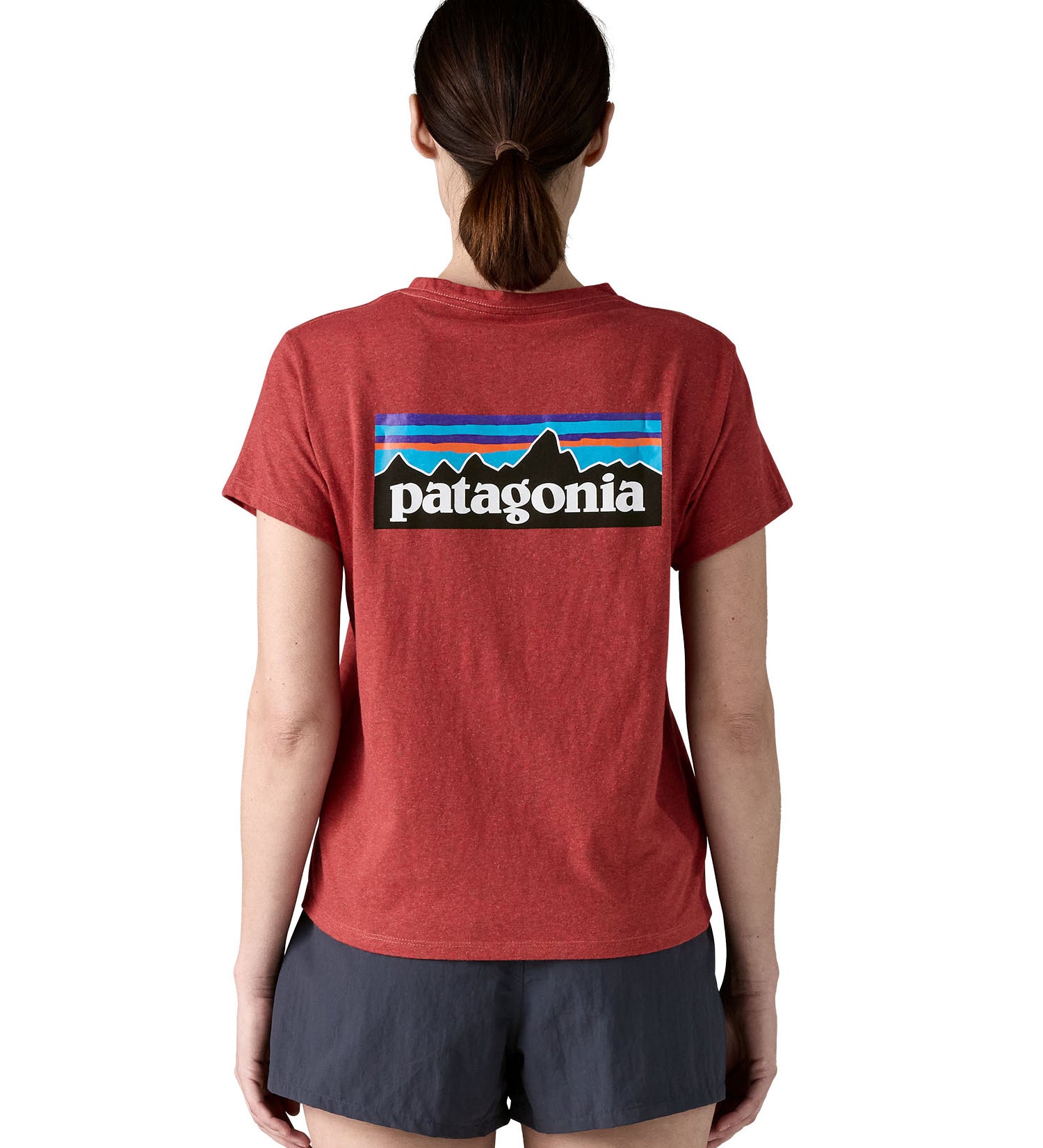 A woman wearing the Patagonia sequoia red short sleeve shirt showing the large brand logo printed on the back of the t-shirt