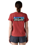 A woman wearing the Patagonia sequoia red short sleeve shirt showing the large brand logo printed on the back of the t-shirt