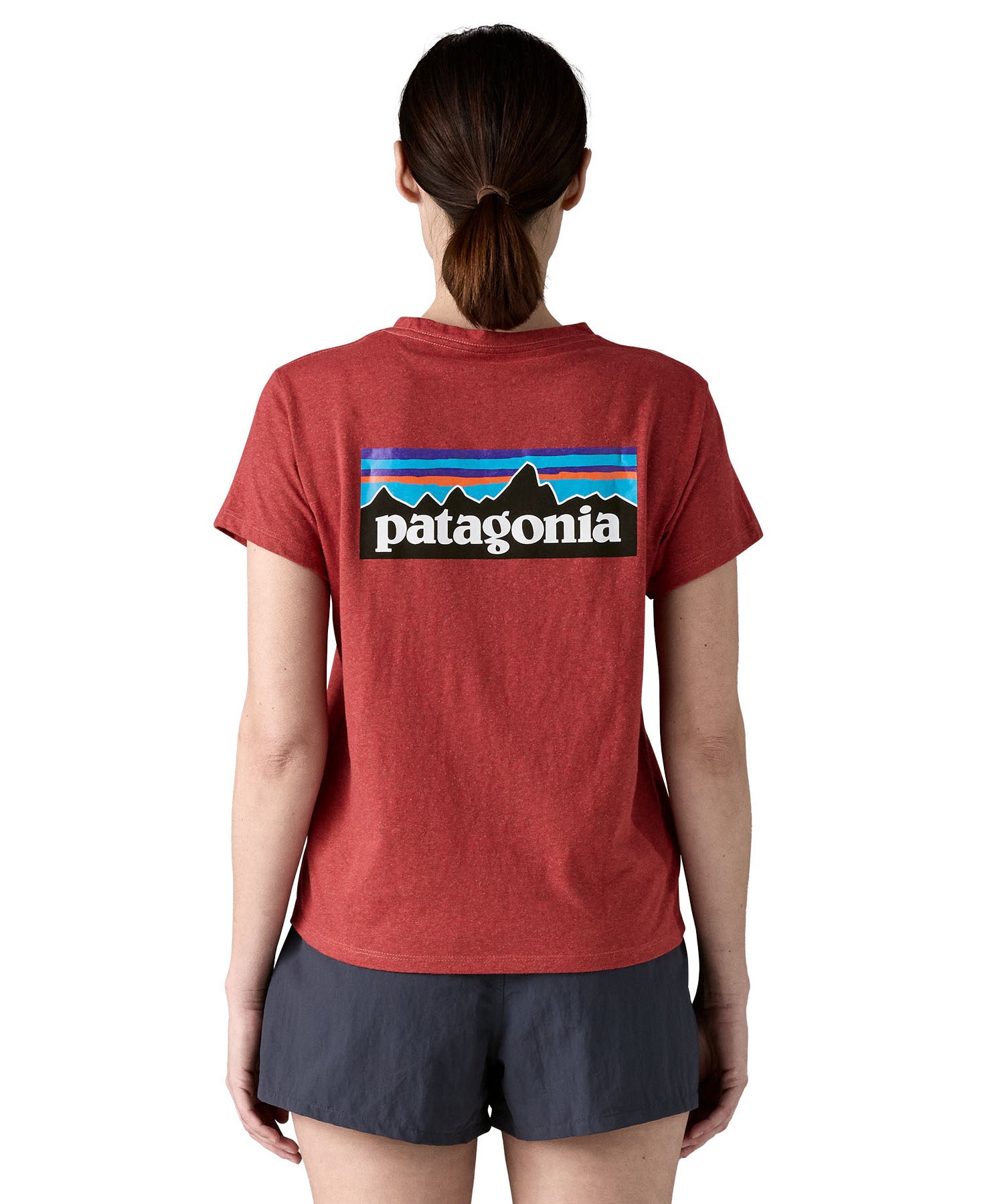 A woman wearing the Patagonia sequoia red short sleeve shirt showing the large brand logo printed on the back of the t-shirt