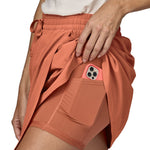 Patagonia women's fleetwith skort in a pastel orange colour worn by a woman side pocket detail