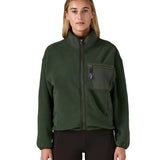 Woman wearing the Patagonia women's synchilla fleece jacket in dark green. Full zip jacket with zippered chest pocket and handwarmer pockets.