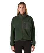 Woman wearing the Patagonia women's synchilla fleece jacket in dark green. Full zip jacket with zippered chest pocket and handwarmer pockets.